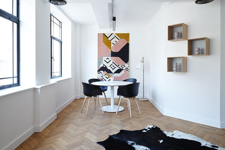 Designerskie czarne krzesła i biały okrągły stolik w małym salonie.