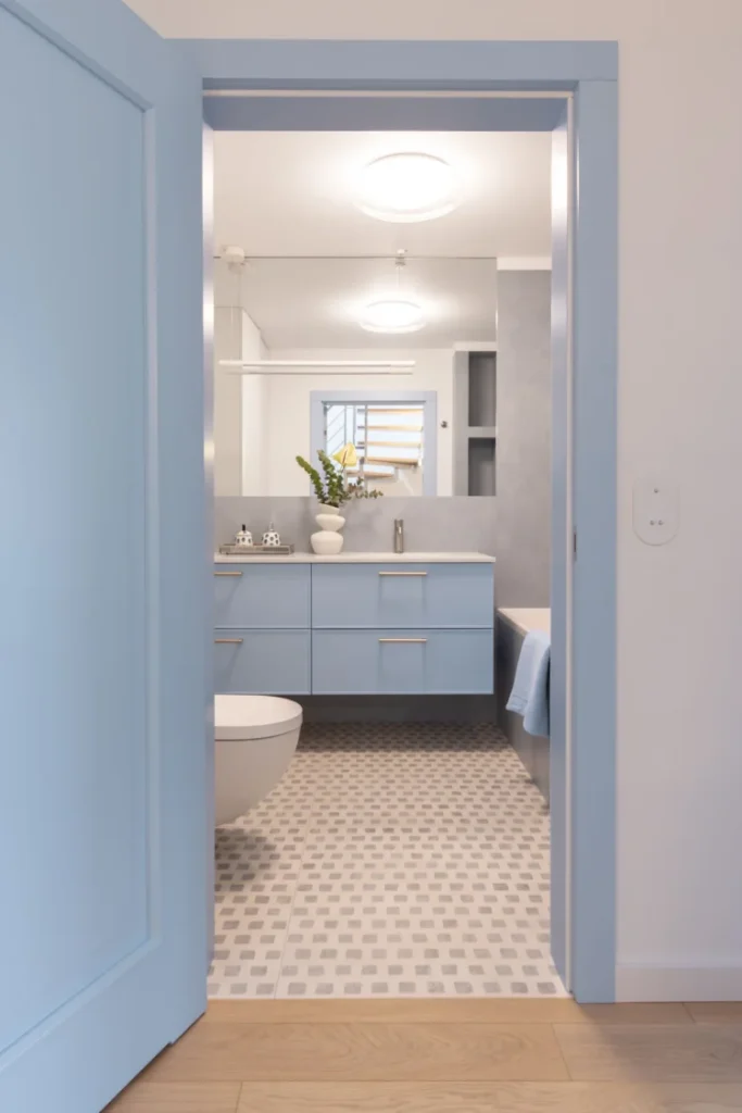Nowoczesna łazienka z błękitną szafką podumywalkową, geometryczna mozaika podłogowa, błękitne drzwi, projekt JLW Studio